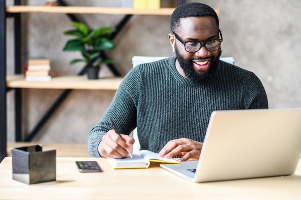 Male freelancer with beard wearing glasses working on a laptop. Find out if freelancers need insurance at the Coverdash blog.