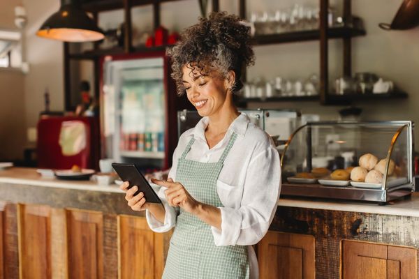 Small business owner in bakery looking at tablet searching for answers to small business insurance questions.